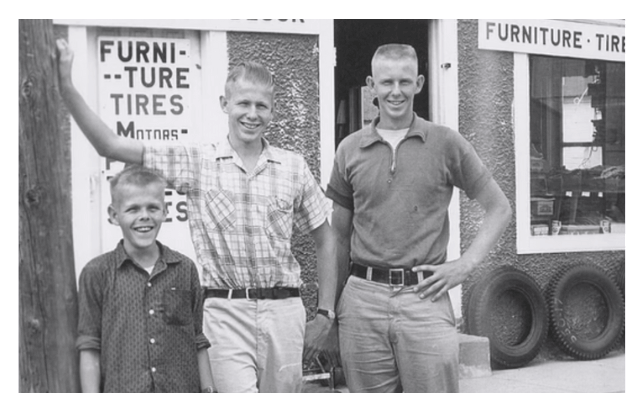 Three boys standing together of different ages outside a storefront near Lake Okoboji.