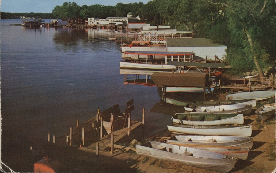 A postcard from 1993 of Lake Okoboji with canoes along the shoreline. 