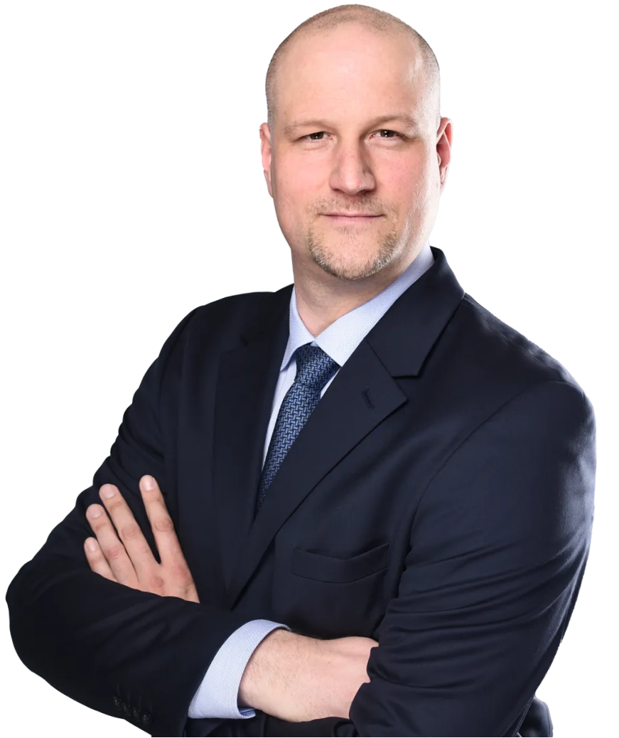 Geschäftsmann mit dunklem Anzug und Krawatte, die Arme vor der Brust verschränkt.