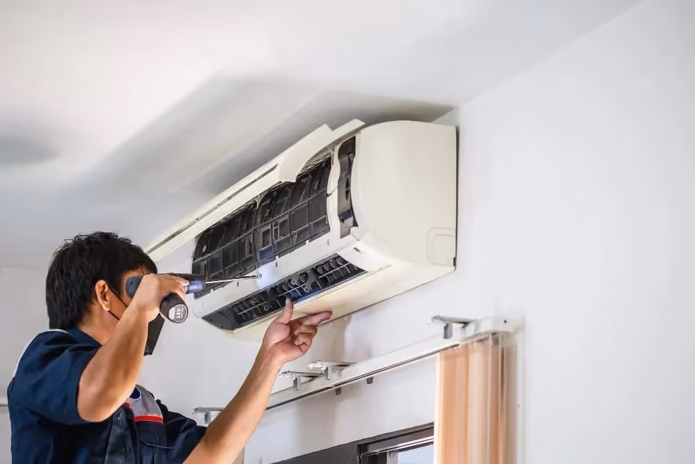 Technician using screwdriver on split air conditioner.
