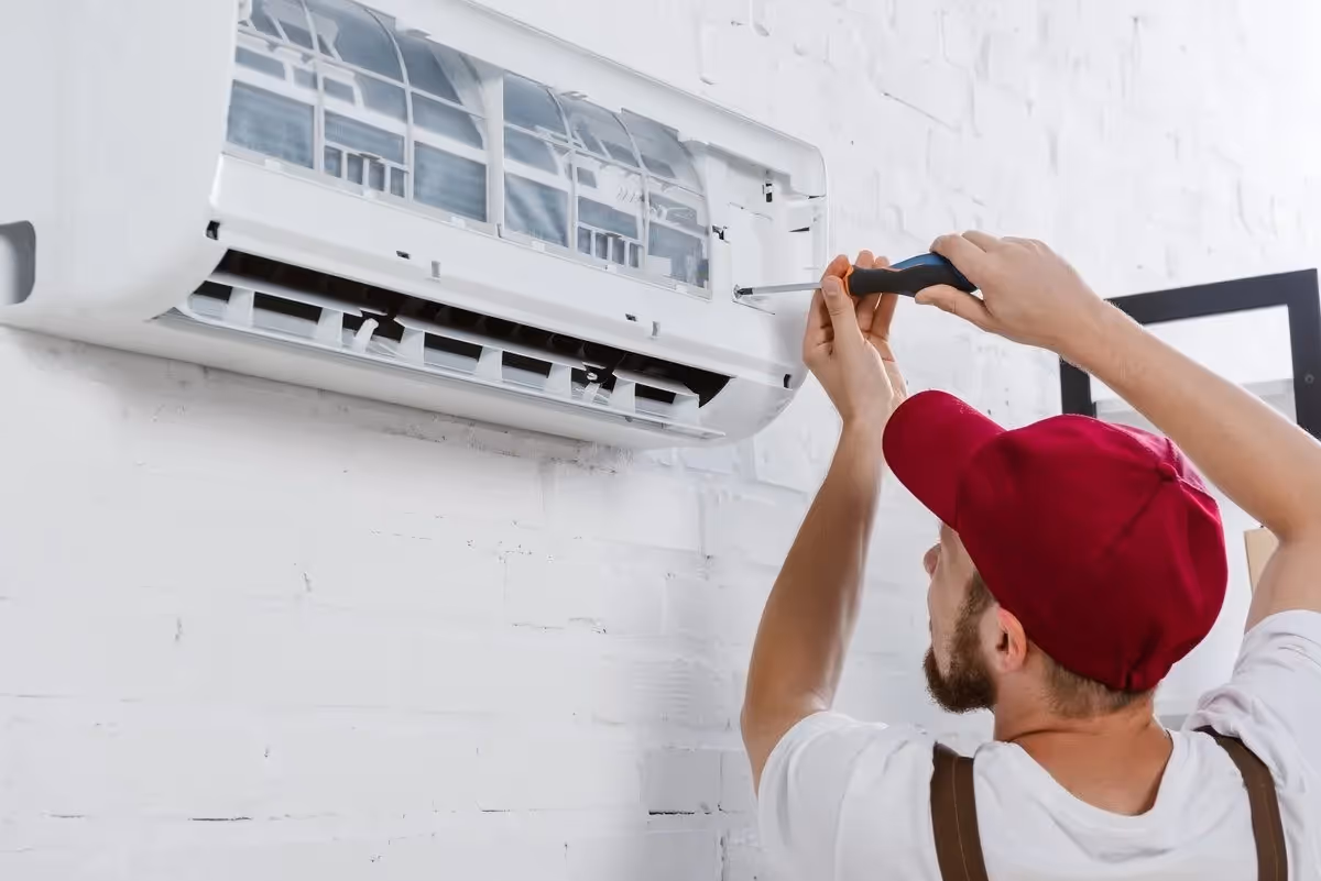 Technician repairs air conditioner with a screwdriver.