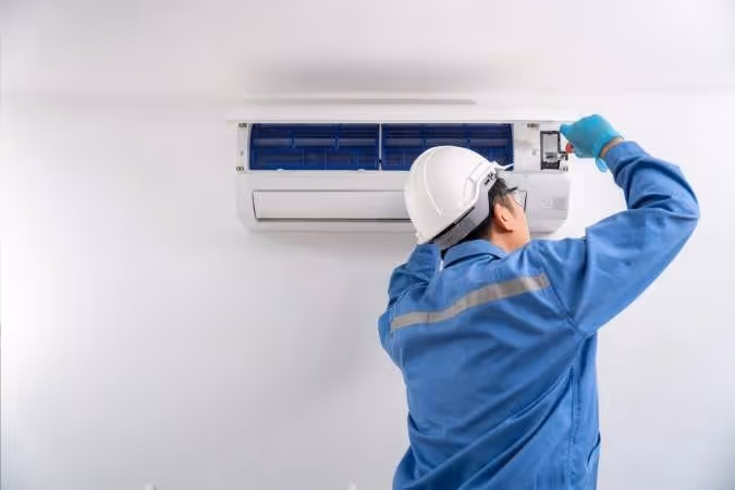 Technician in uniform repairs mini-split AC.