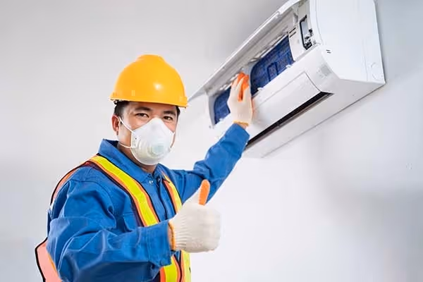 Technician cleaning AC gives thumbs-up.