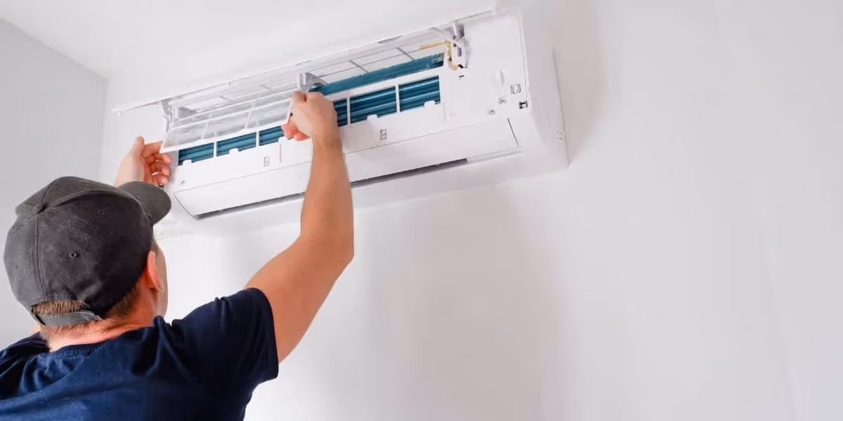 Man cleans filter of mini-split AC.