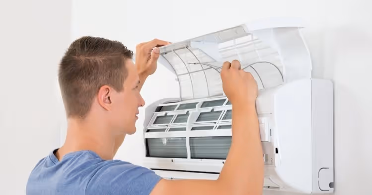 Man opens AC unit to check filter.