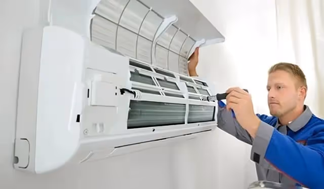 Technician services a wall-mounted mini-split AC.