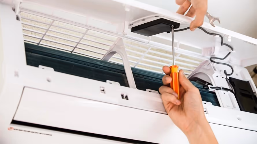 Hands repair AC unit with screwdriver and wrench.