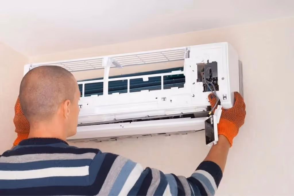 Technician in gloves repairs a wall AC.