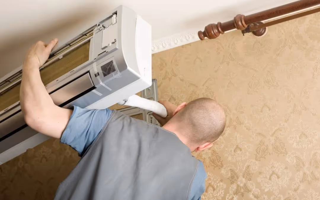 Man installing mini-split air conditioner indoors.