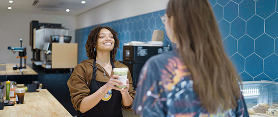 A woman standing in front of a counter holding a drink.