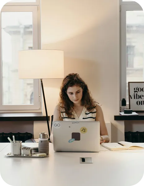 A woman sitting at a table using a laptop computer.