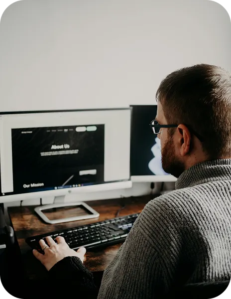 A man sitting in front of two computer monitors.