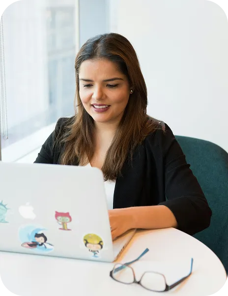 A woman sitting at a table using a laptop computer.