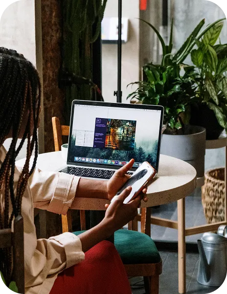 A woman sitting at a table with a laptop and cell phone.
