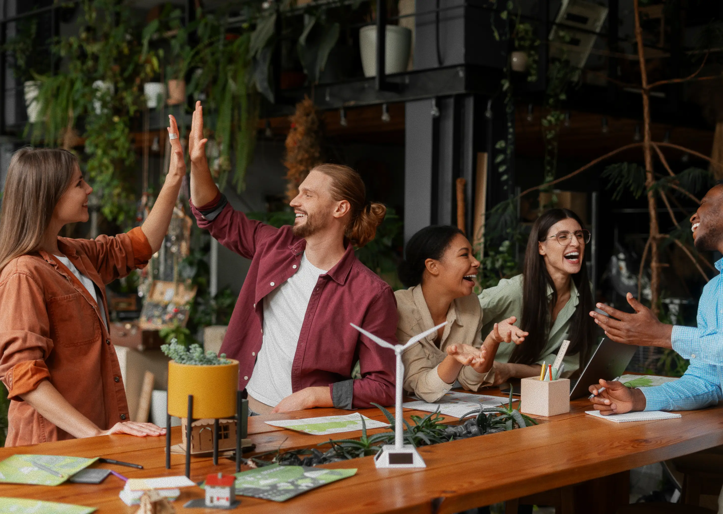 Classmates high-fiving across a table during a lively group study session.