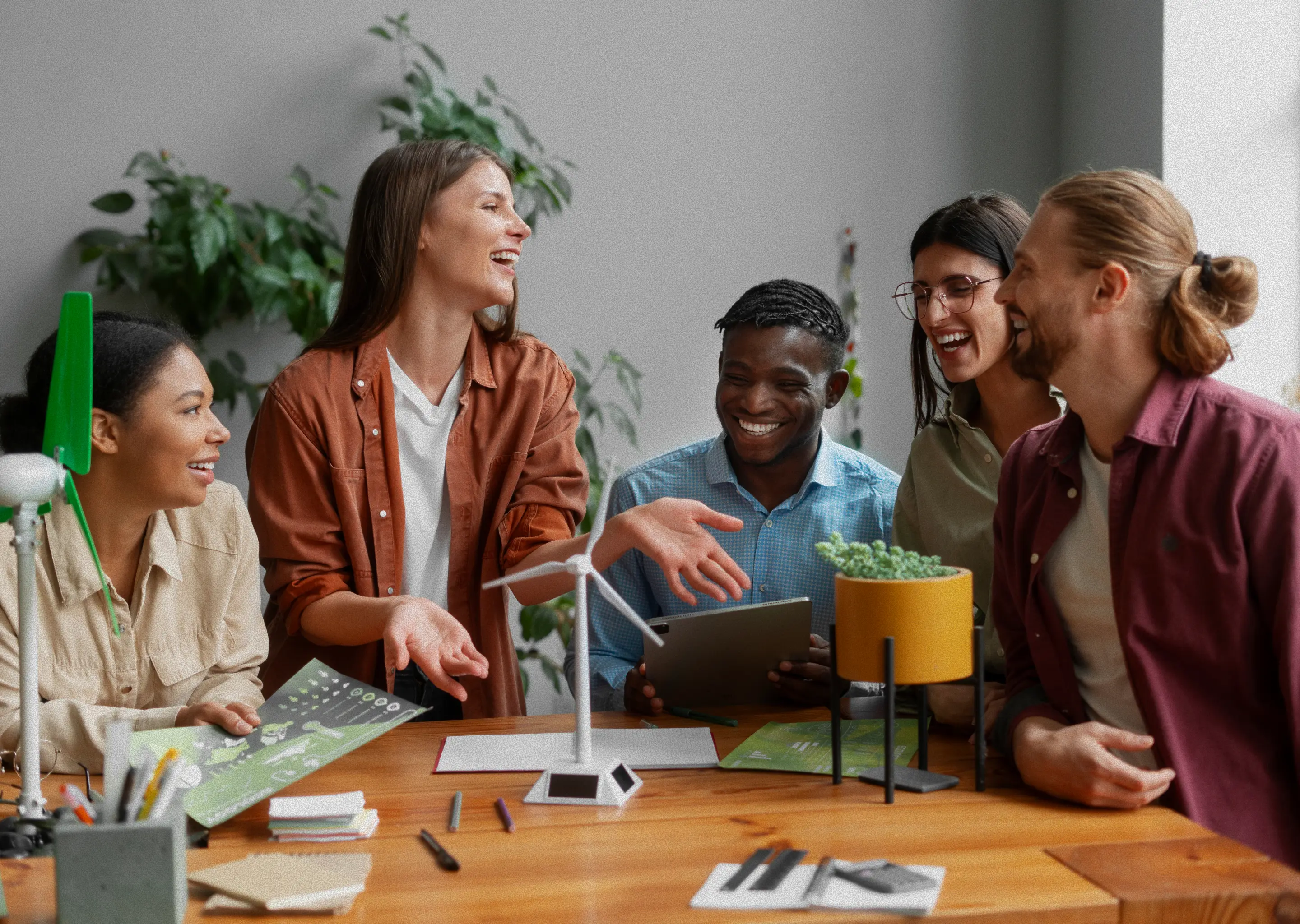 Students smiling and laughing during a group discussion around a classroom table.