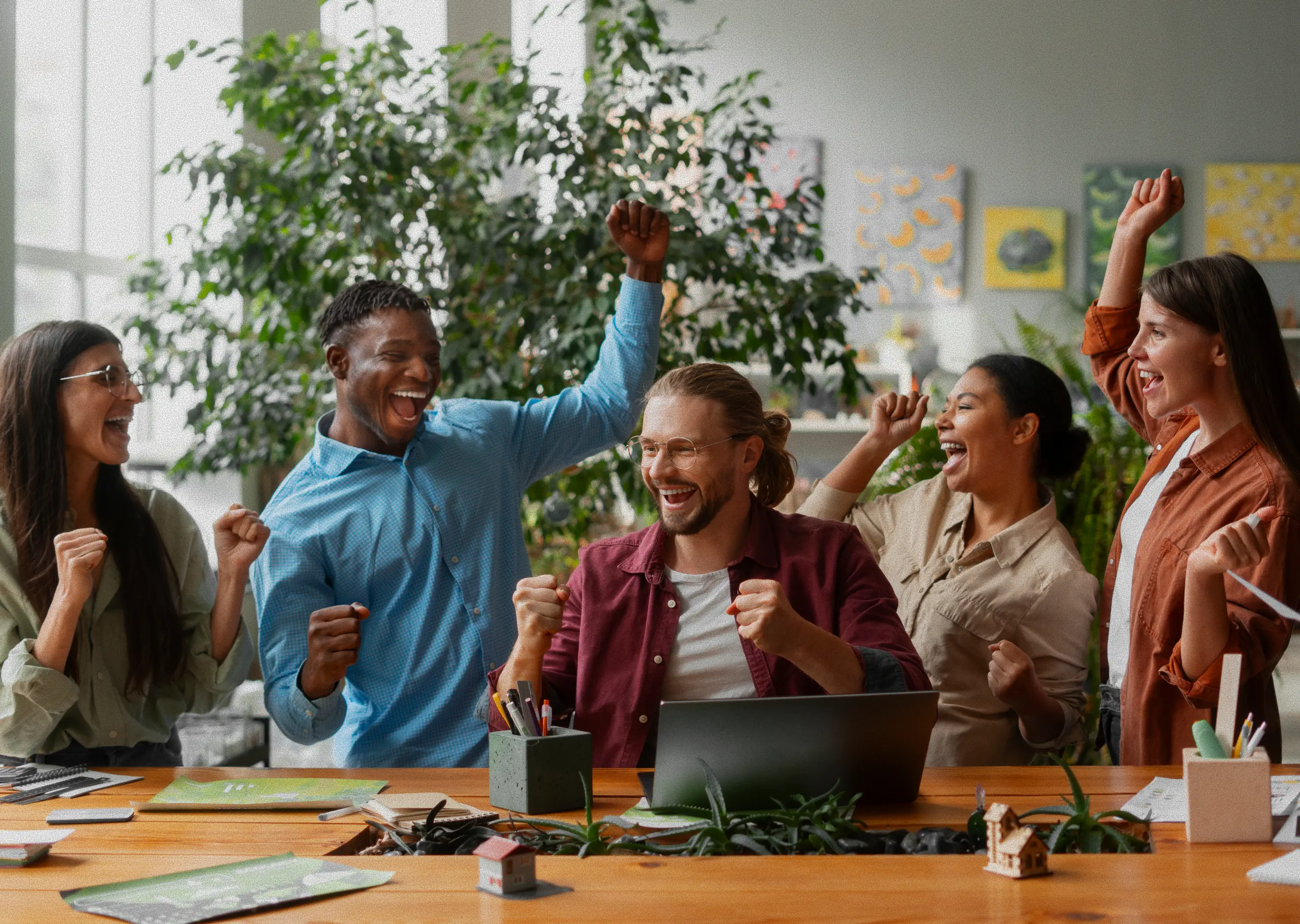 Students cheering and celebrating success together around a study table.