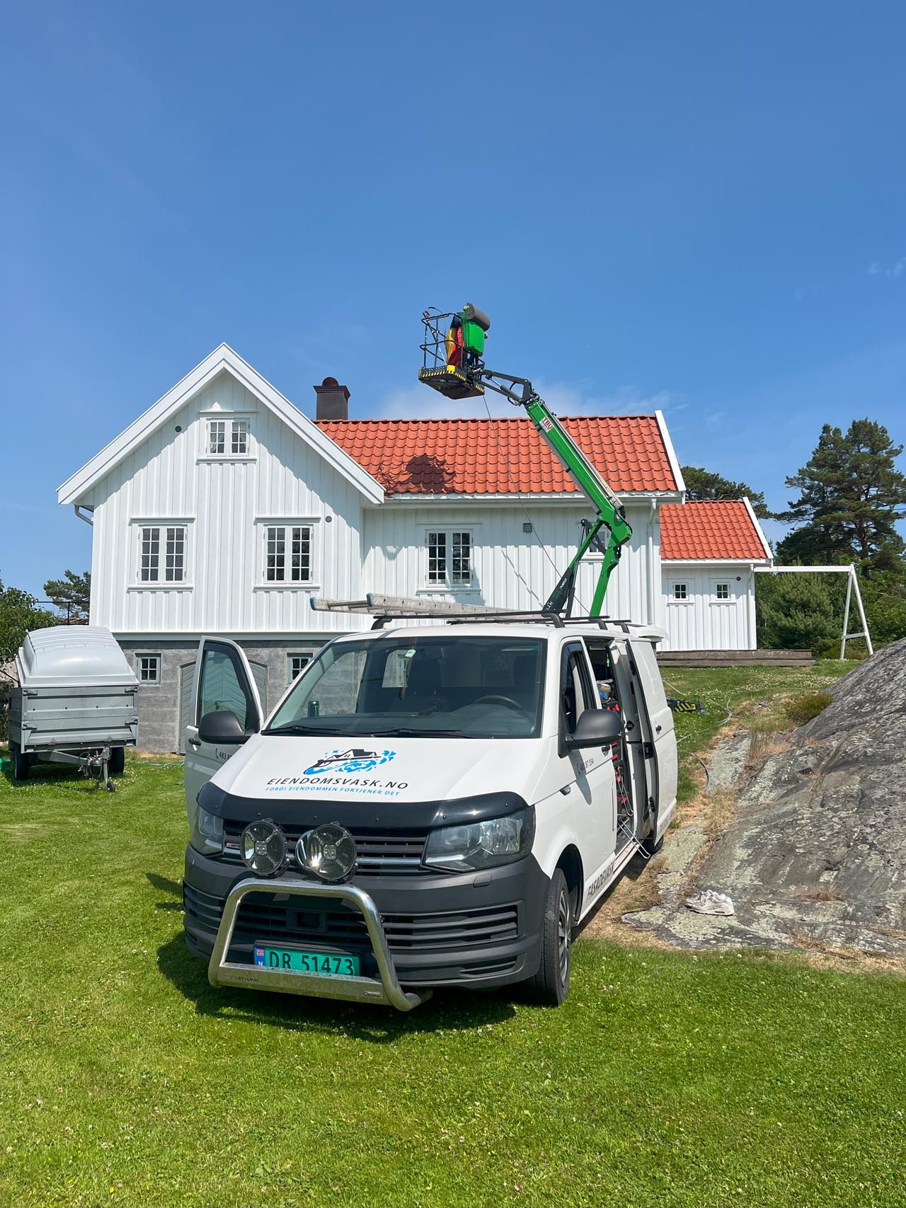 Eiendomsvask som er hos en kunde osm skal gjøre takvask, der en ansatt i bedriften står på en lift og inspiserer husets tak