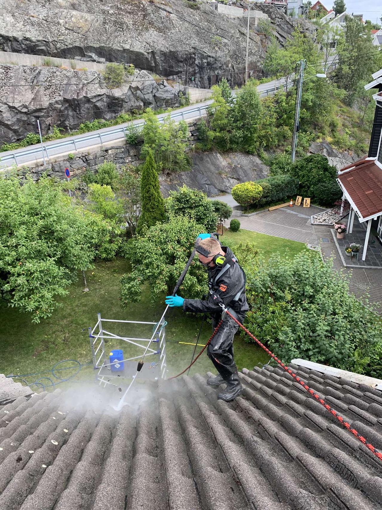 Bendik i Eiendomsvask AS som vasker taket på et hus