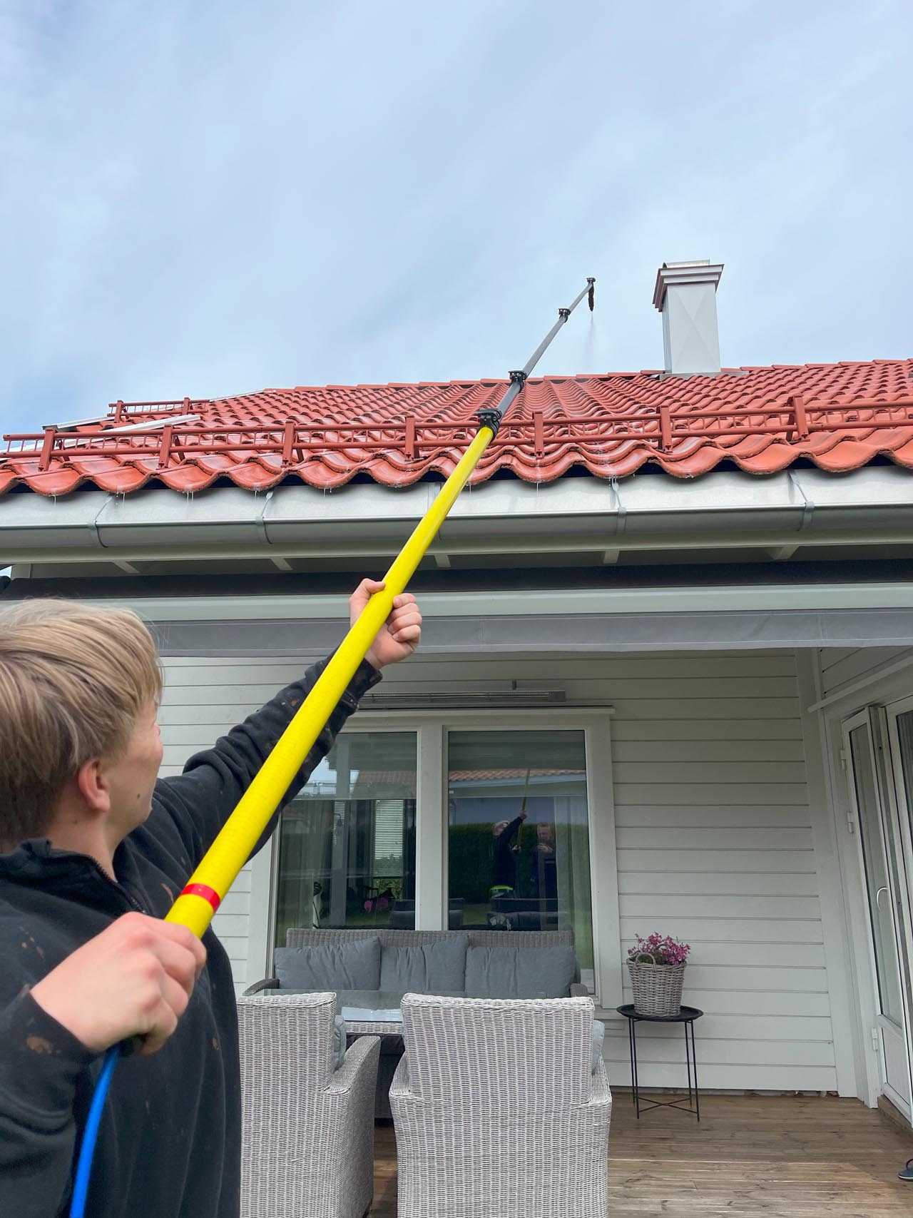 Bendik fra Eiendomsvask AS som vasker et tak på et hus