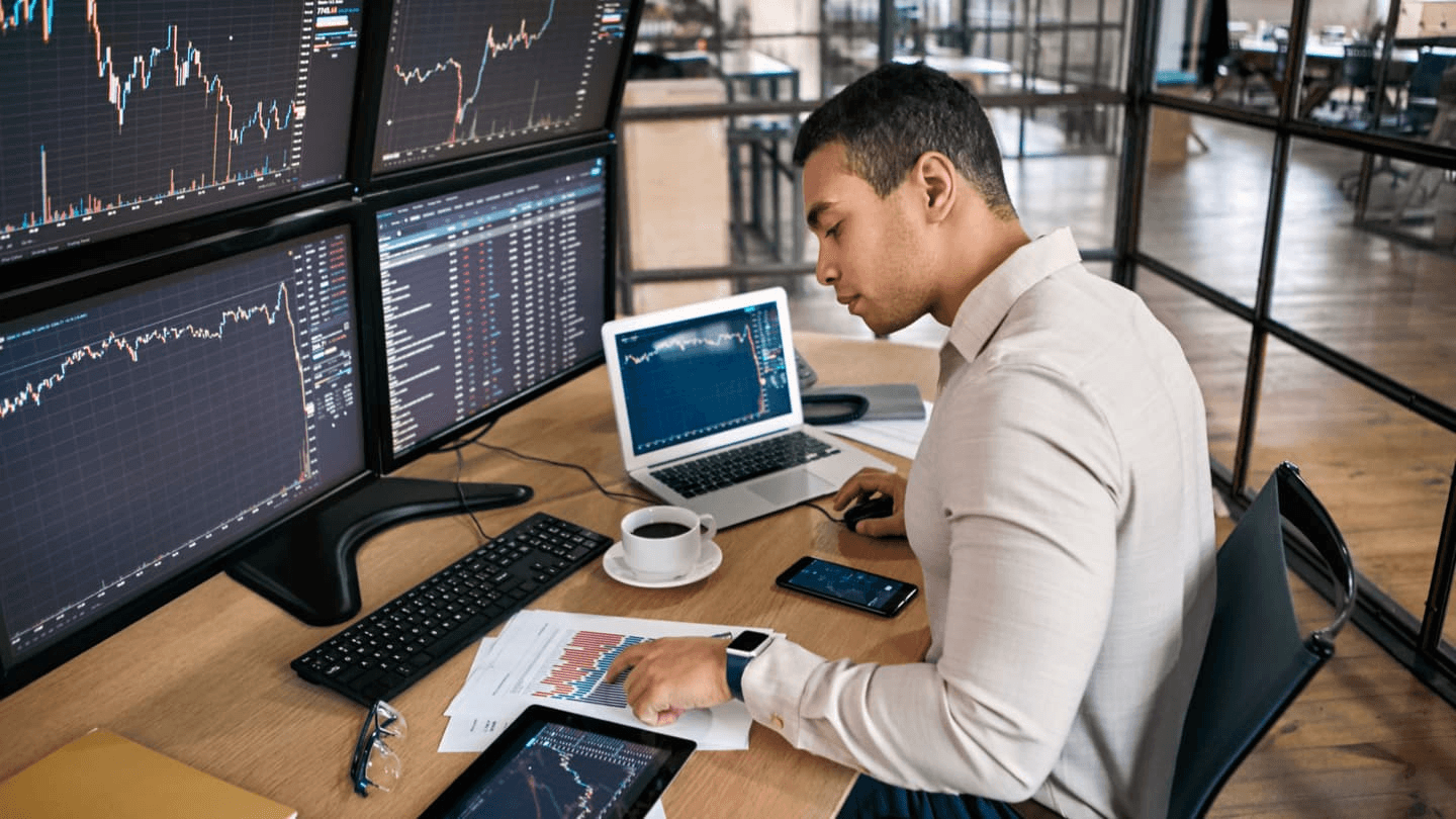 Man analyzing financial data across screens - Forex Trading Course