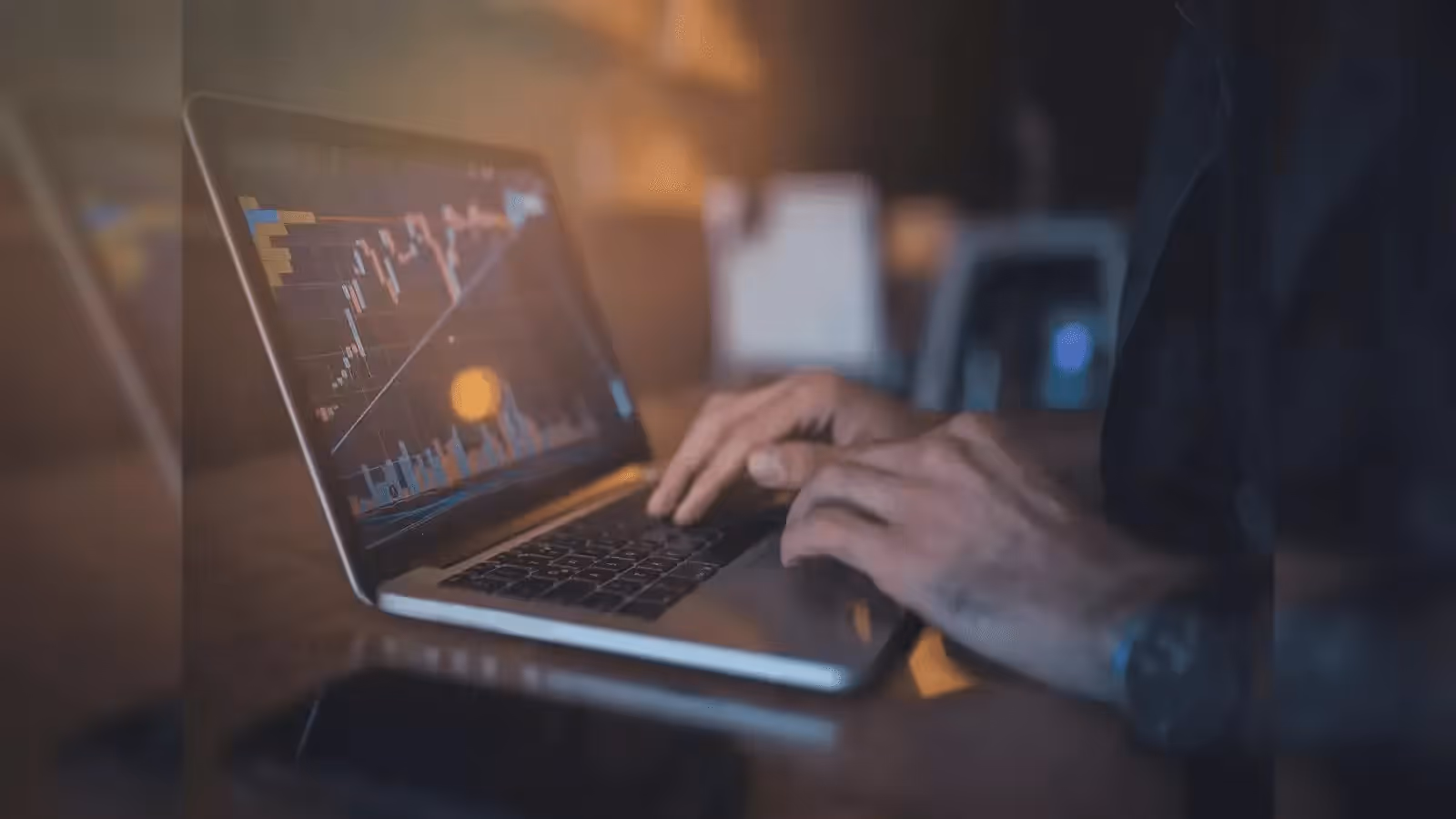 Person typing on laptop with stock charts - FTMO vs FundedNext Comparison