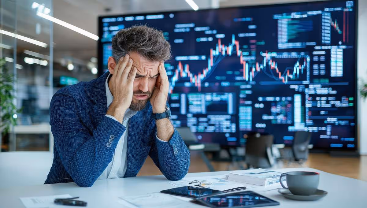Stressed businessman with headache analyzing declining stock market data. Concept of financial loss