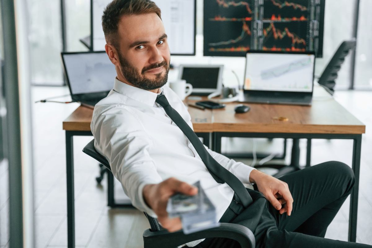 Giving lot of money.,. Holding in hand. Businessman is sitting by computer and working in the office