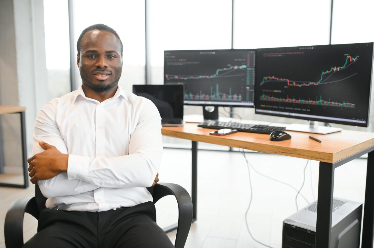 African-American broker works in office using workstation and analysis technology