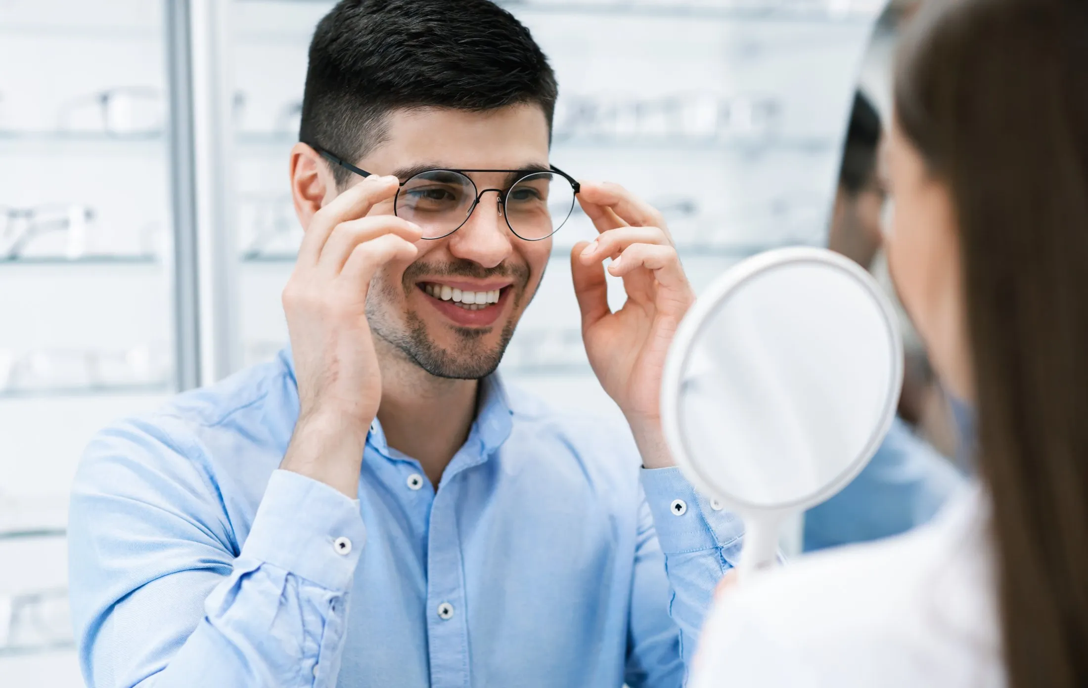 Smiling person trying on new glasses at an optician's office