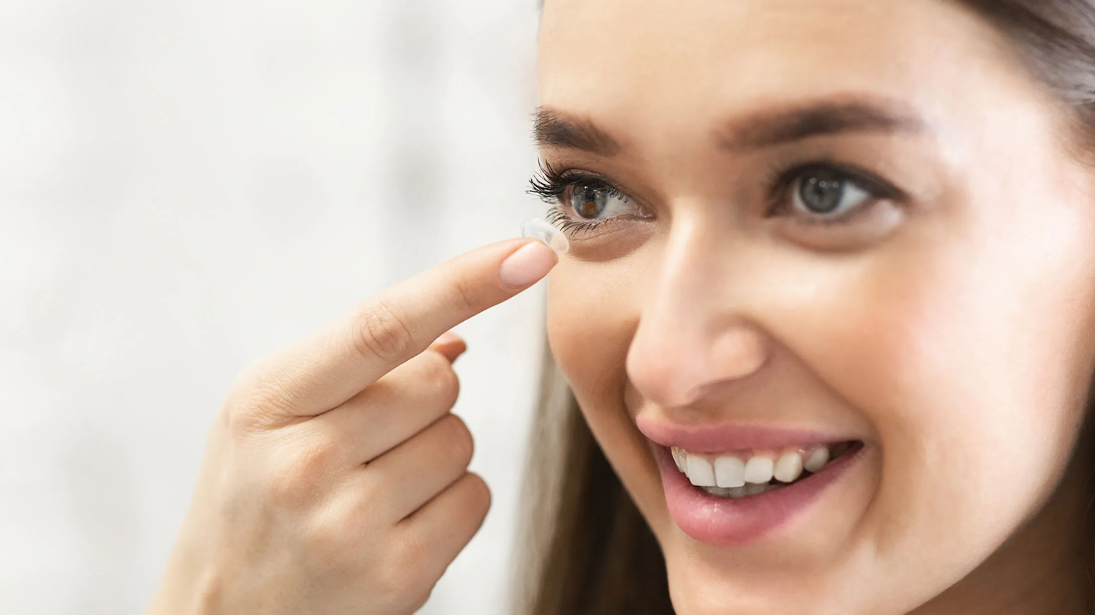 Smiling woman touching skin near eye, showing healthy and radiant complexion