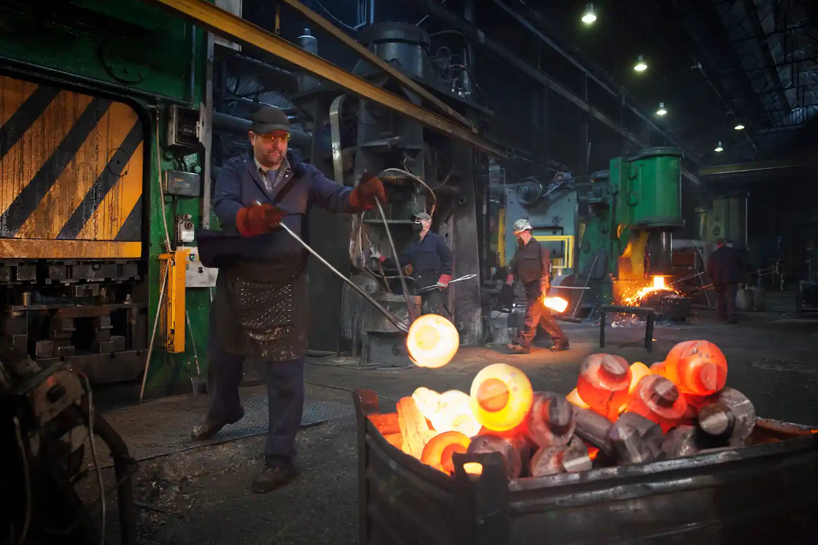 A man holding hot metal with long prongs