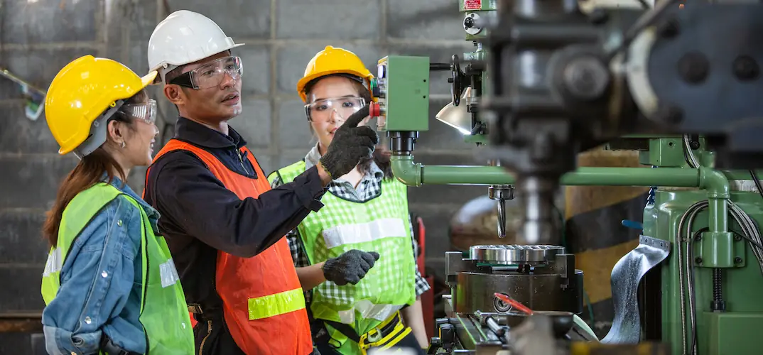 A man and his colleagues pressing a machine button