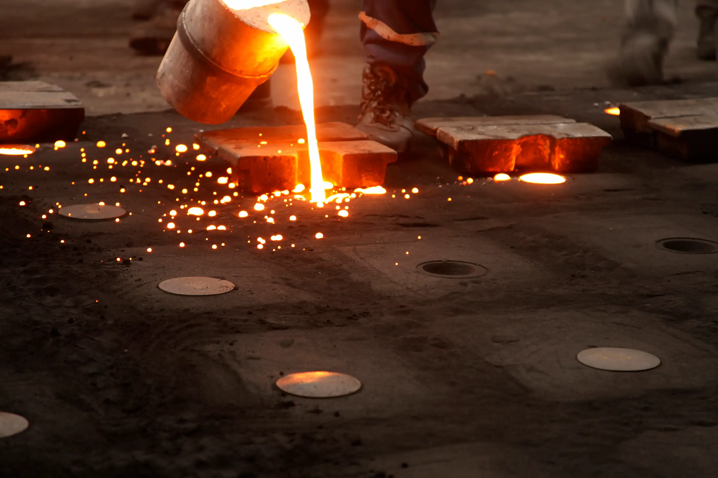 A man pouring melted iron into a sand casting