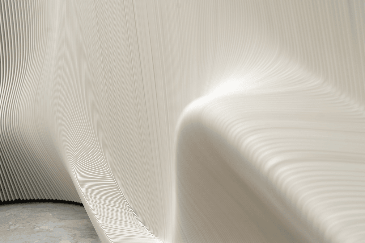 Close-up of a smooth, flowing cream-colored fabric with fine vertical pleats.