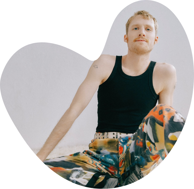 A heart shape cutout, within which contains an image of a young man staring at the camera. 
