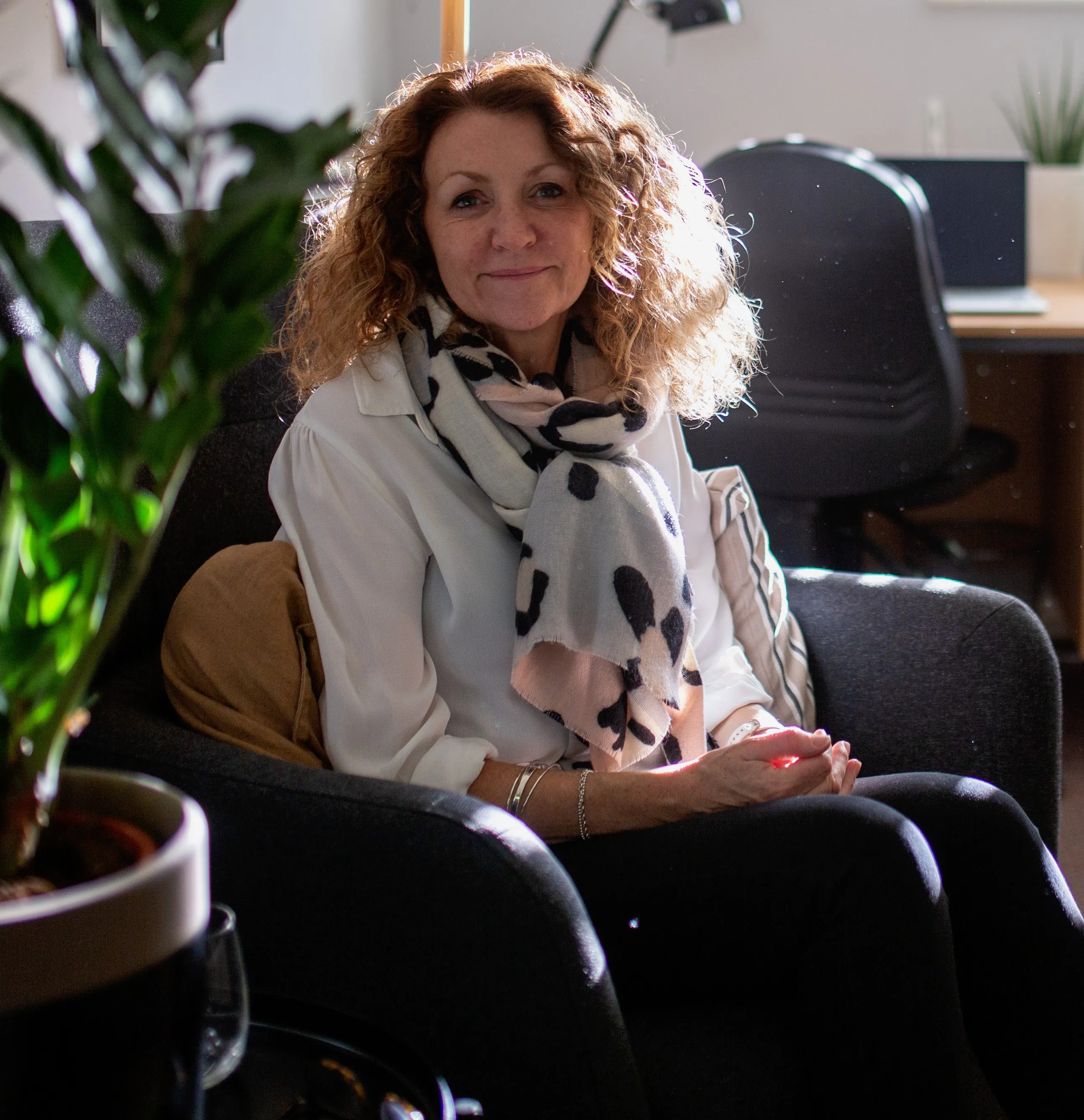 Jeni sitting on a chair inside the cosy Anchor Counselling office