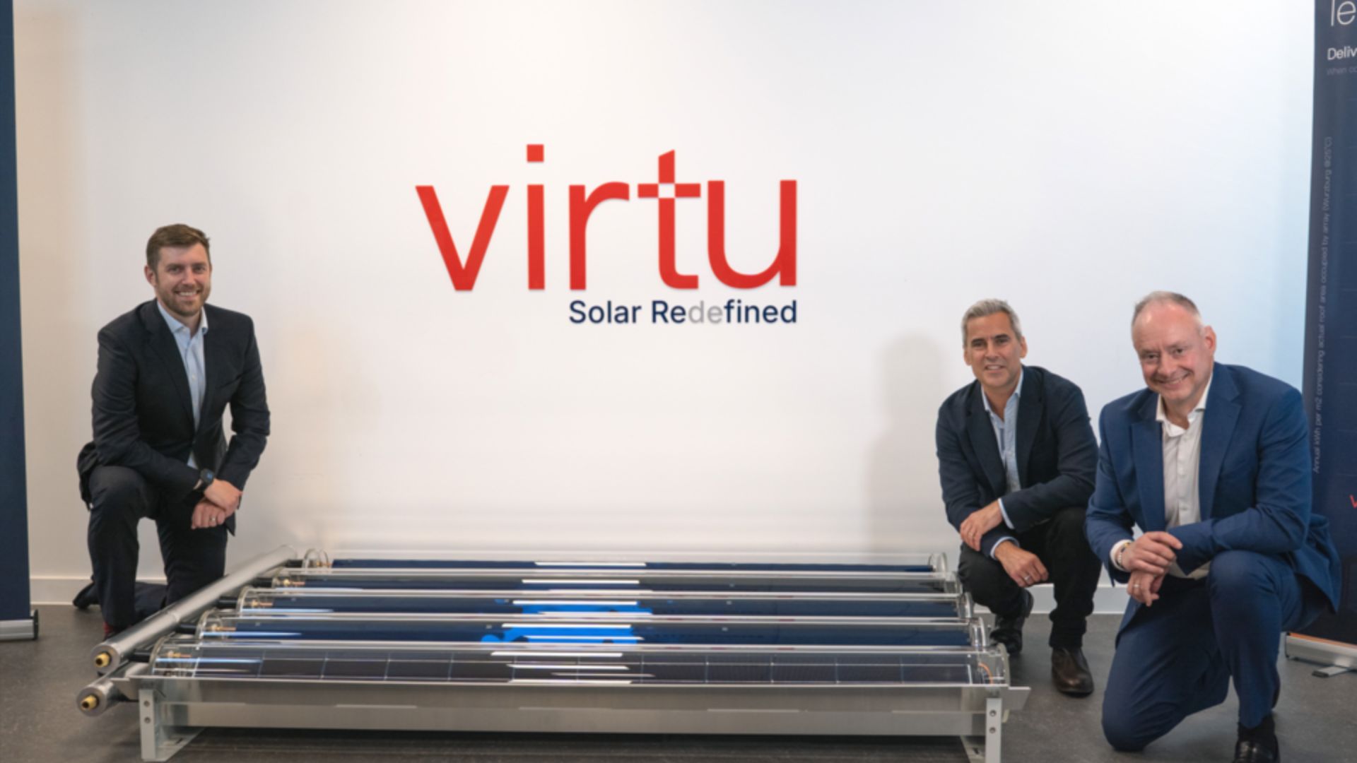 Three men in suits kneel beside tubular solar collector panels in front of a white wall displaying a large red "virtu" logo and the tagline "Solar Redefined".