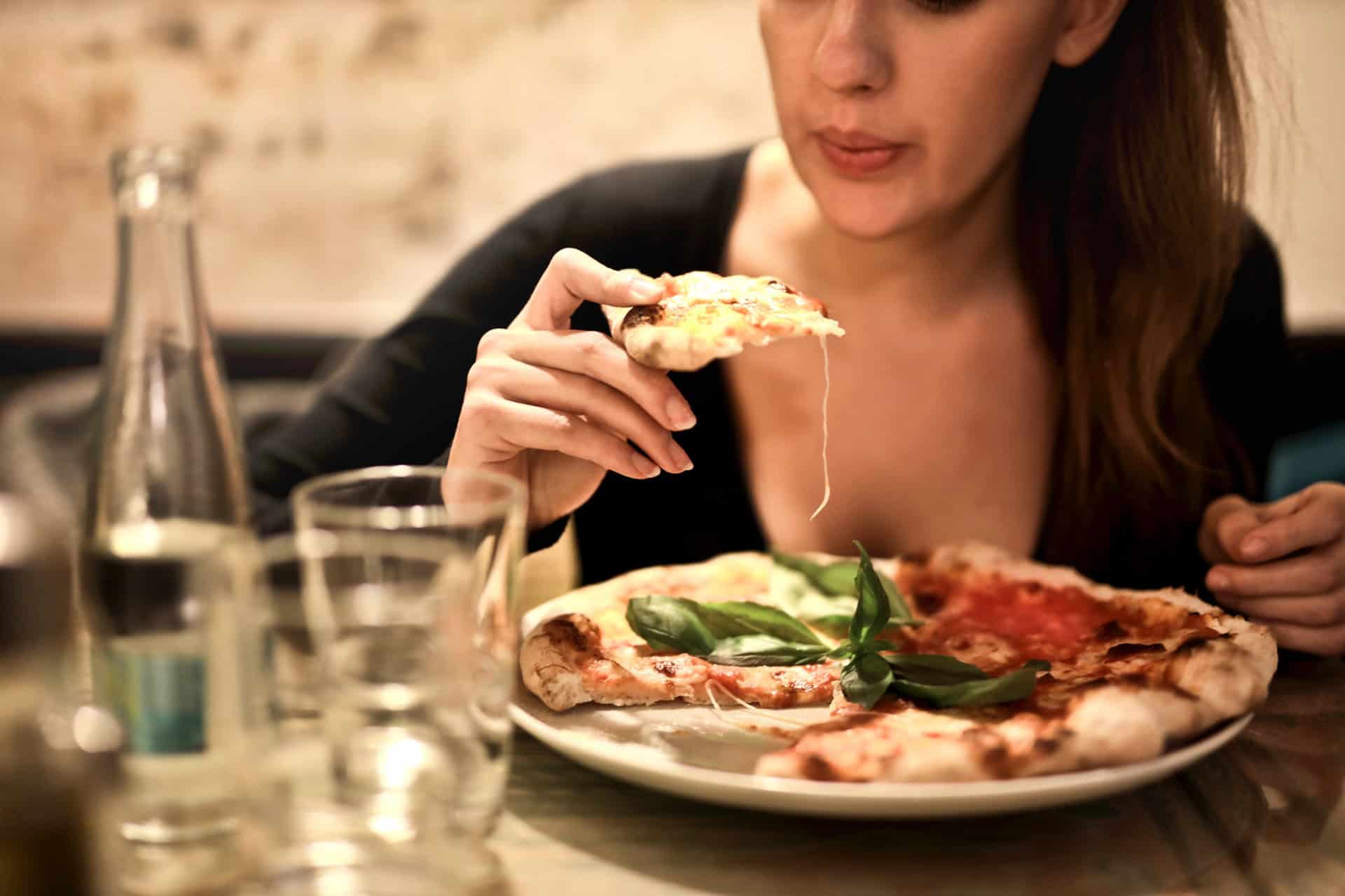 Zdjęcie kobiety jedzącej pizzę w restauracji