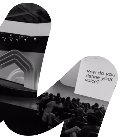 Audience seated in a modern auditorium watching a presentation with the slide displaying the question 'How do you define your voice?' in large text.