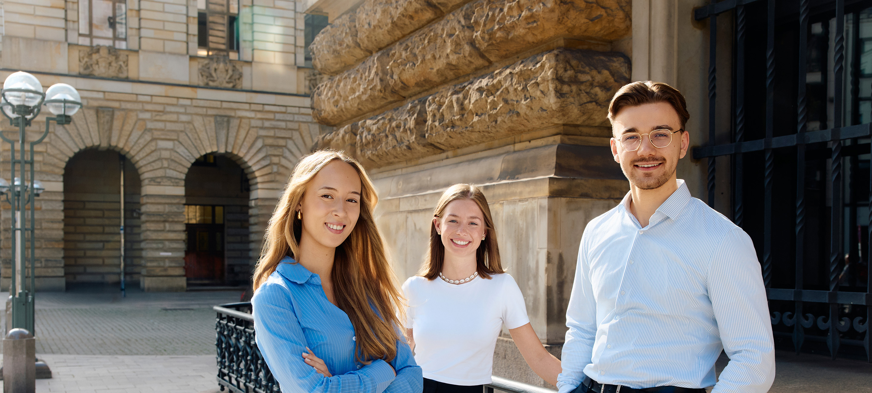 Three young persons in front of a building