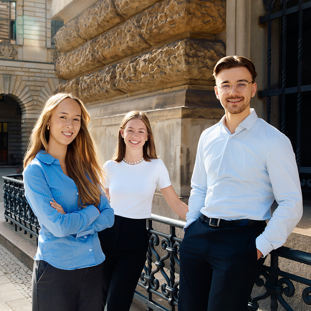 Three persons in front of a building