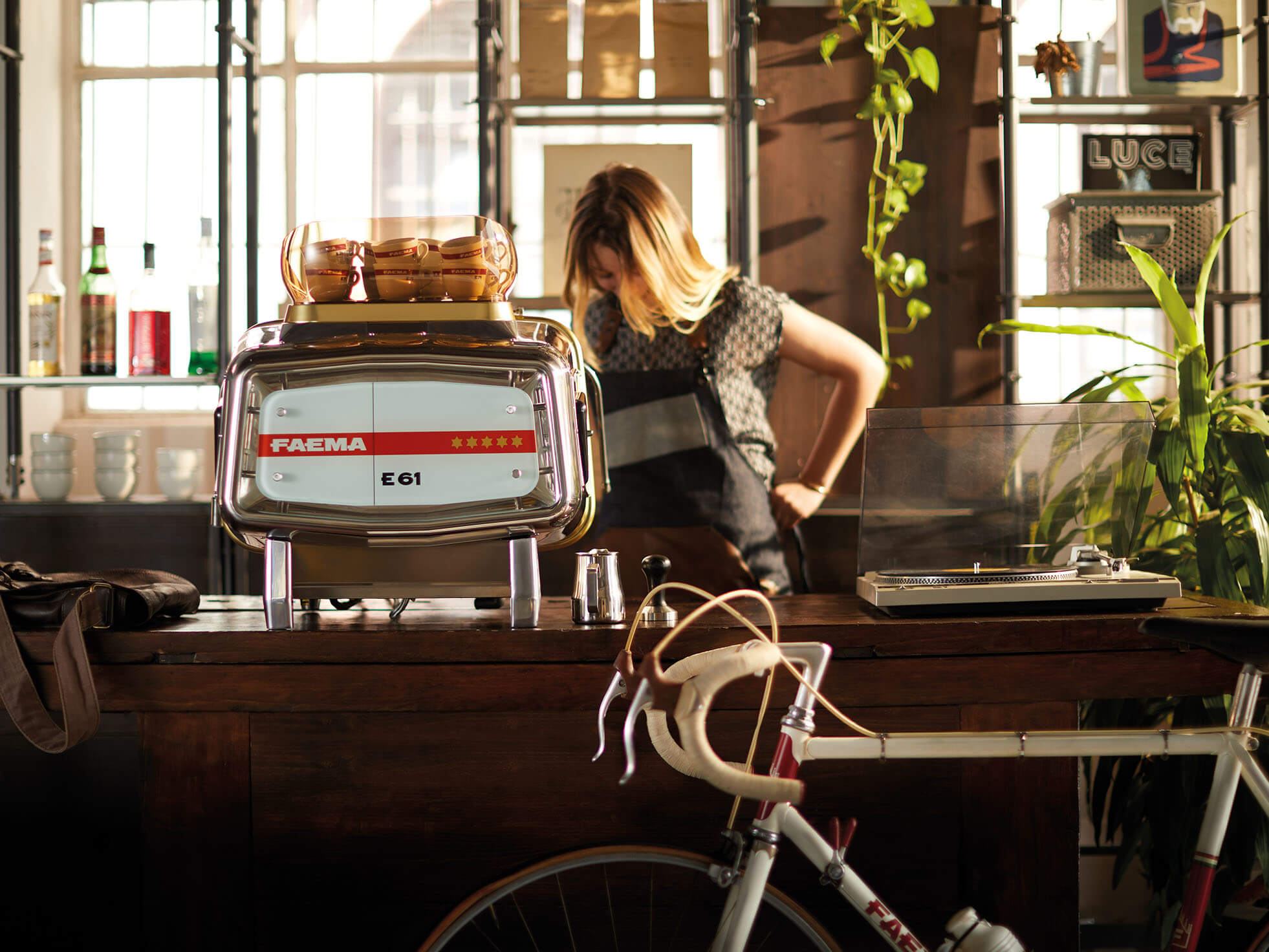 Die Faema E61 Kaffeemaschine steht auf den Bartresen und eine Kellnerin serviert Kaffee