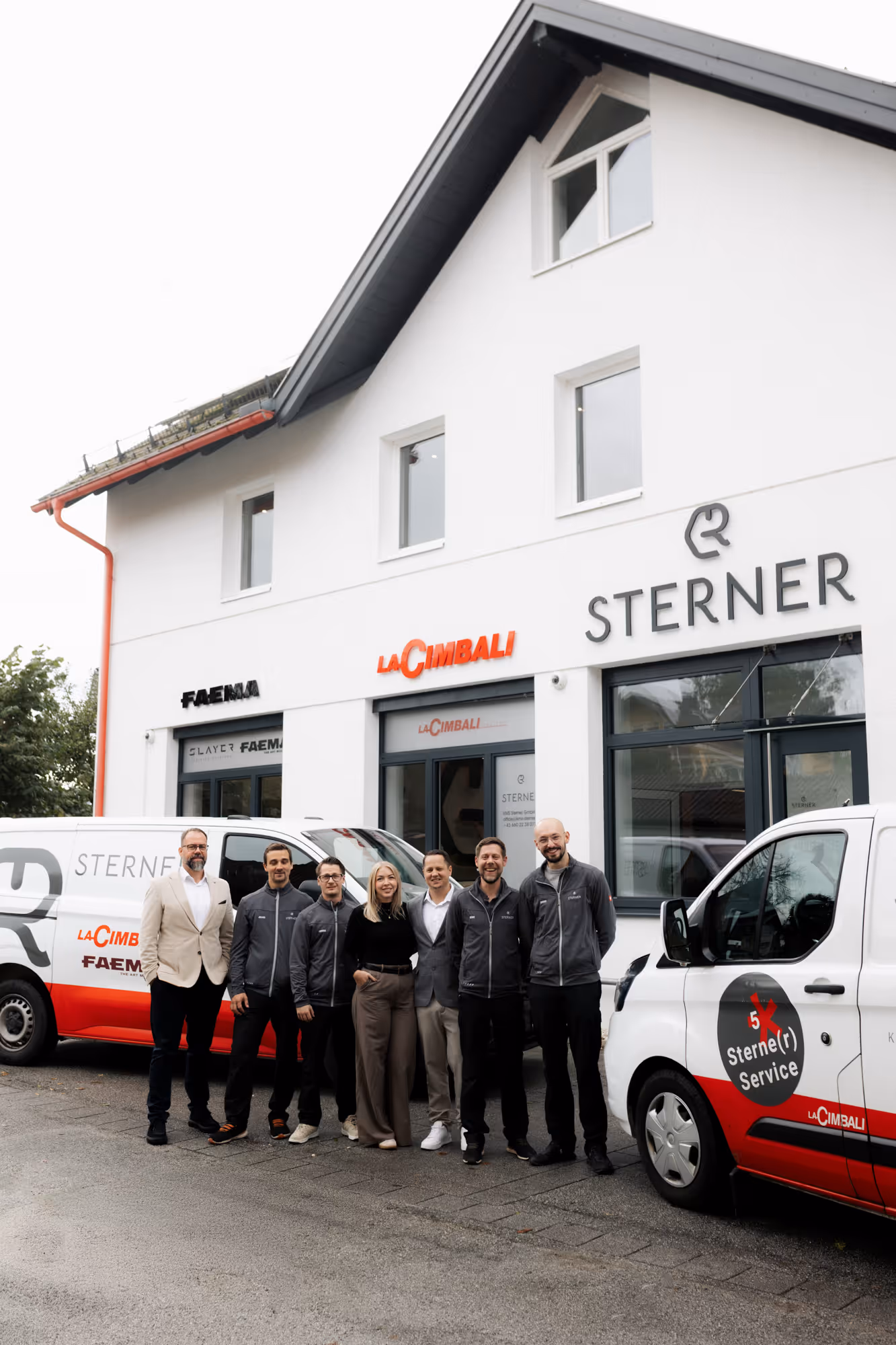 Personen vor einem Firmengebäude und 2 Firmenbusse