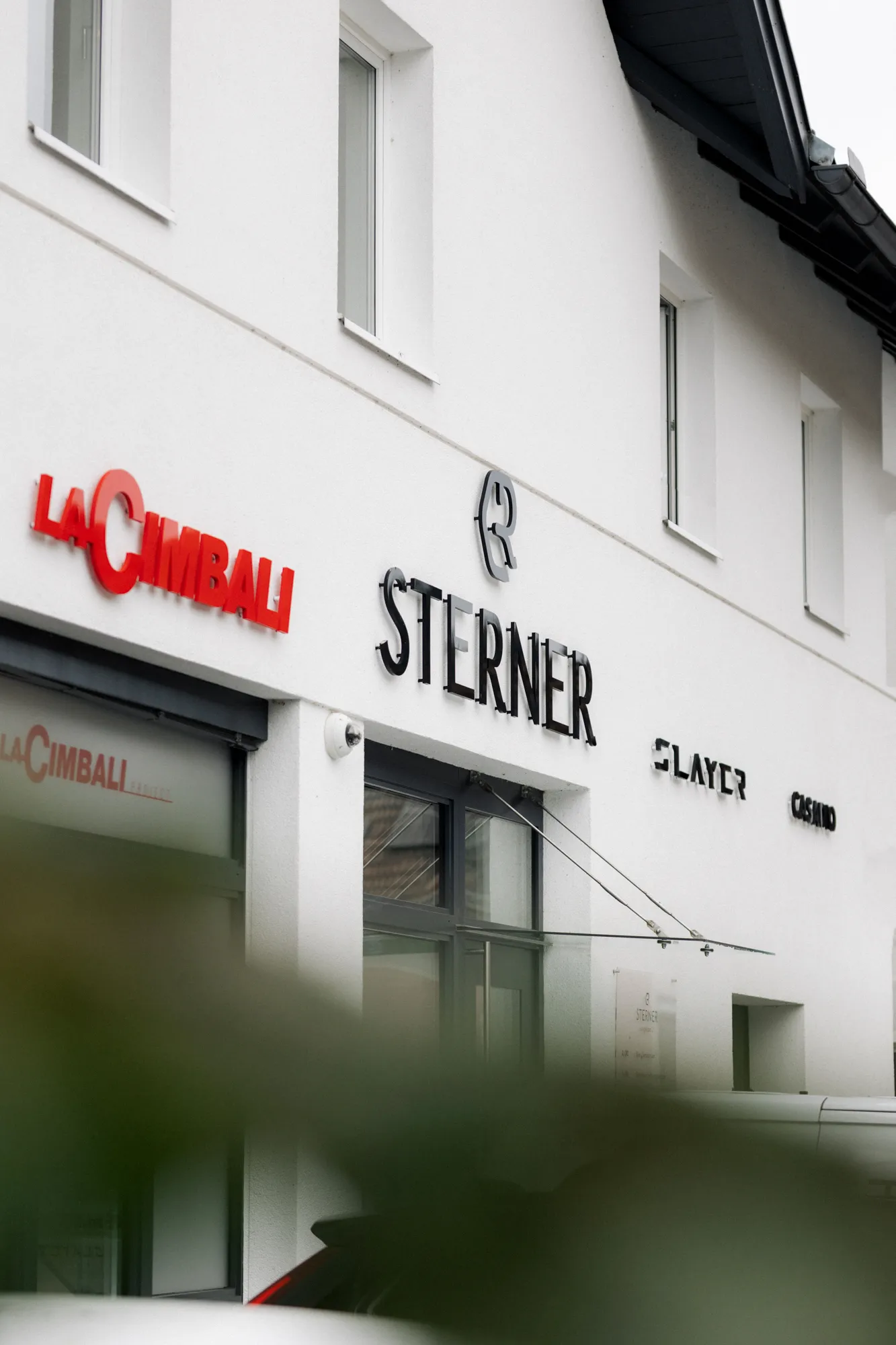 Ein weißes Haus mit Logos auf der Fassade - KMS Sterner in Bergheim