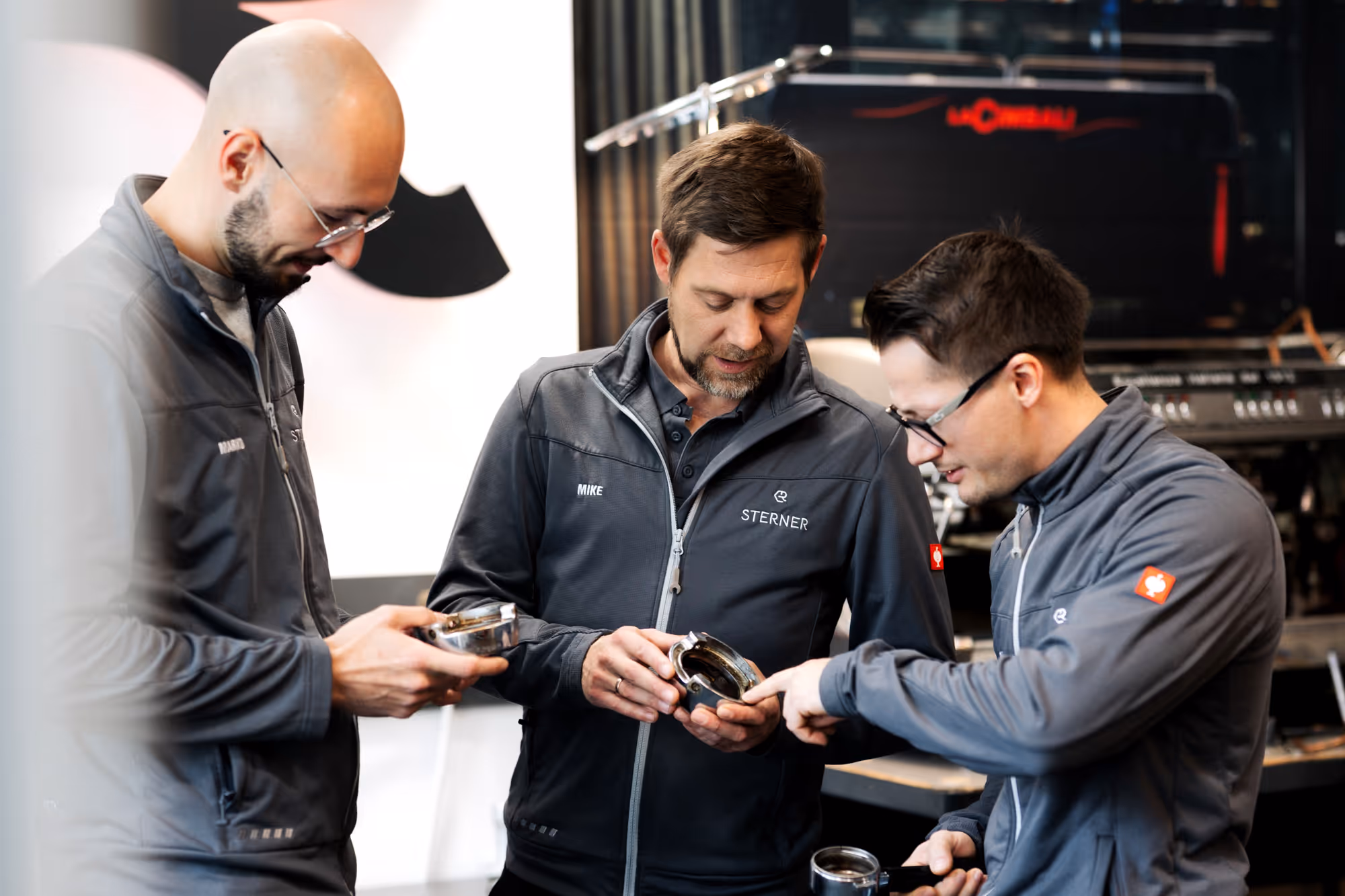 Eine Gruppe von 3 Männern reparieren eine Kaffeemaschine