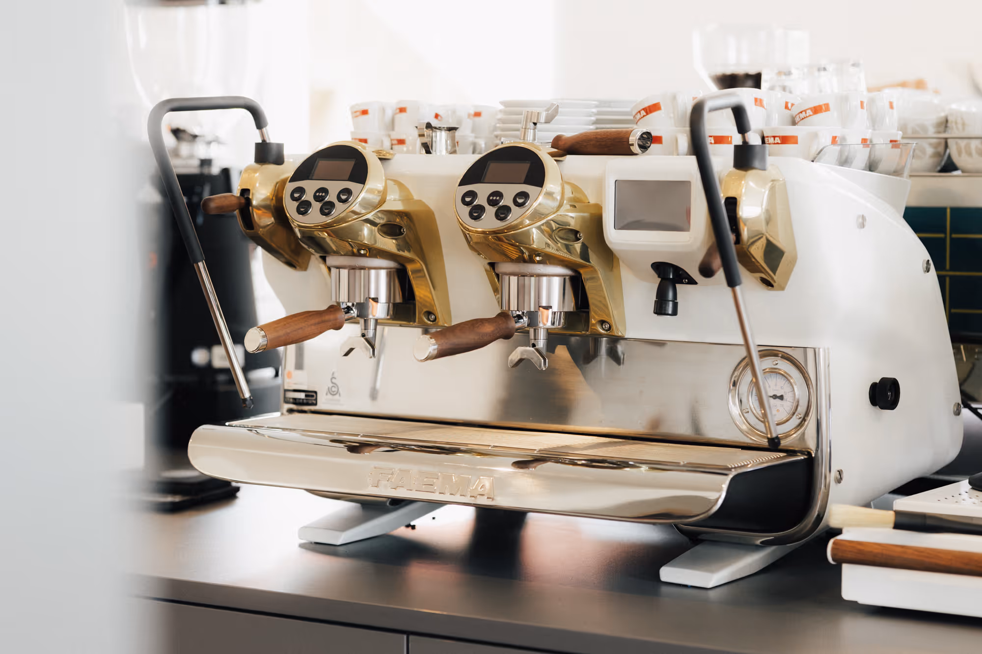 Eine weiß-goldene Siebträgermaschine auf einem Tisch