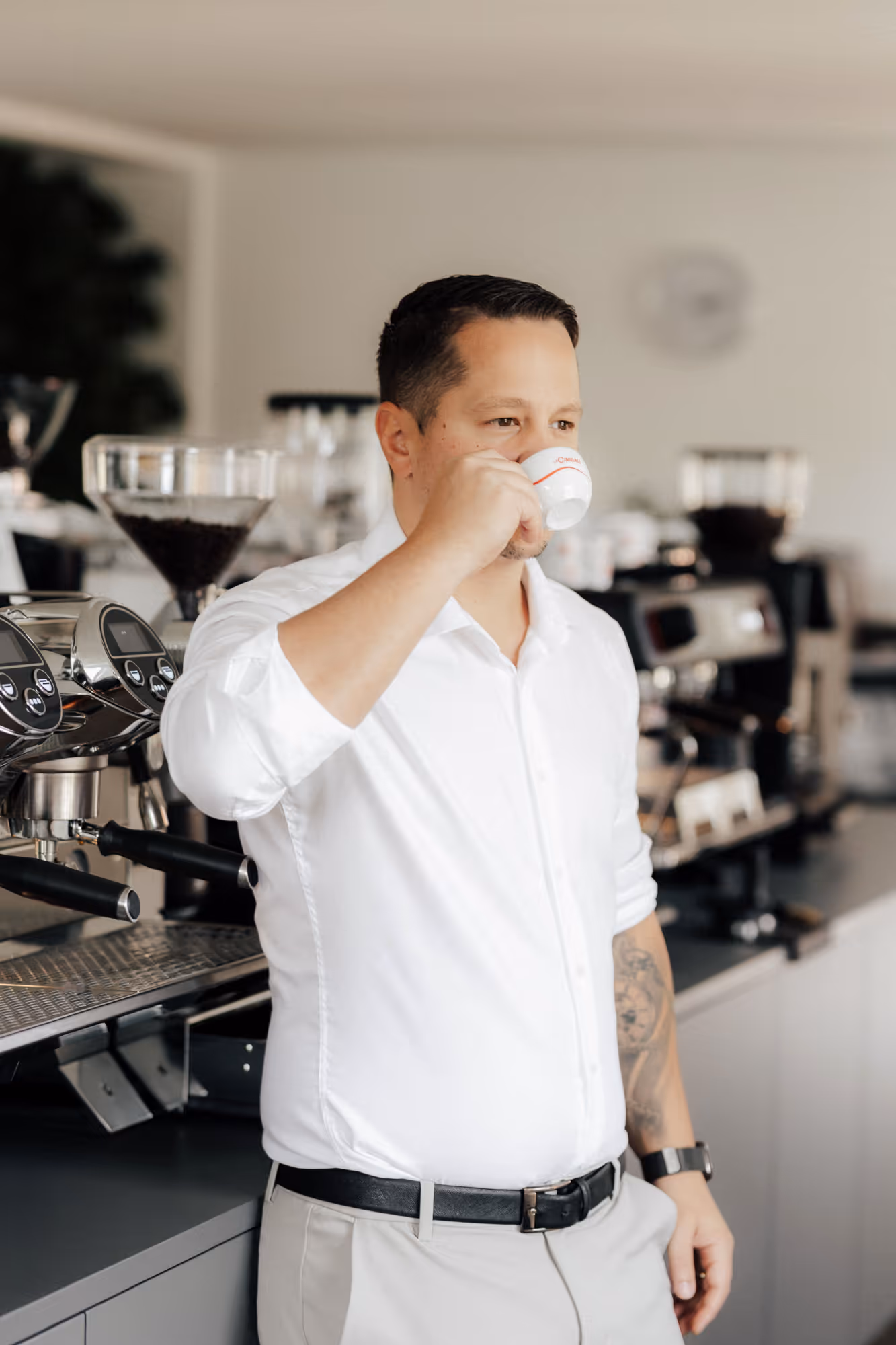 Ein Mann mit weißem Hemd trinkt einen Kaffee