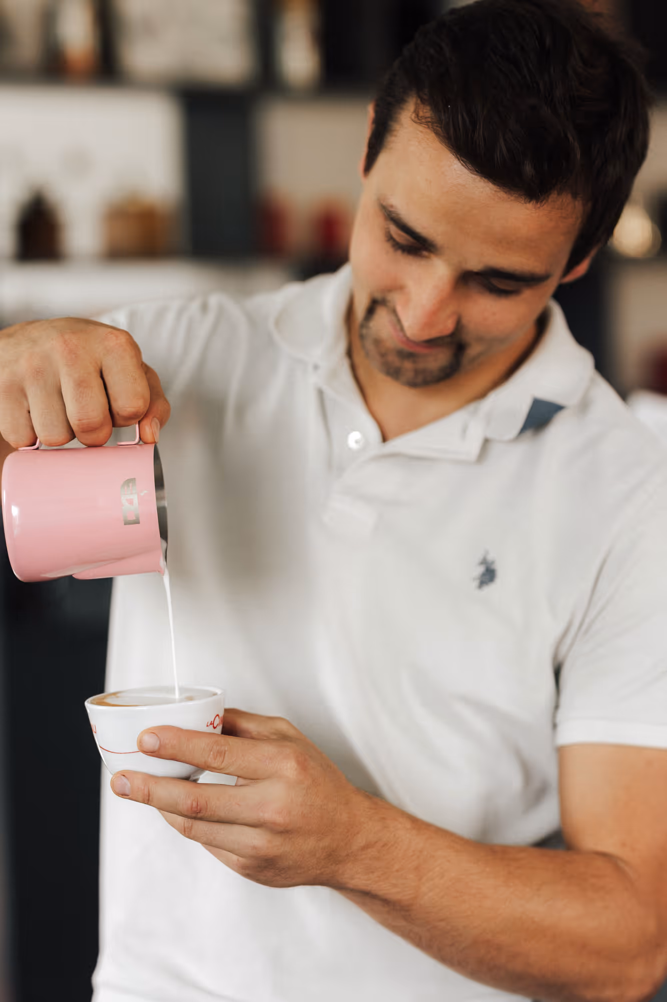 Ein Mann richtet einen Kaffee mit Milchschaum her