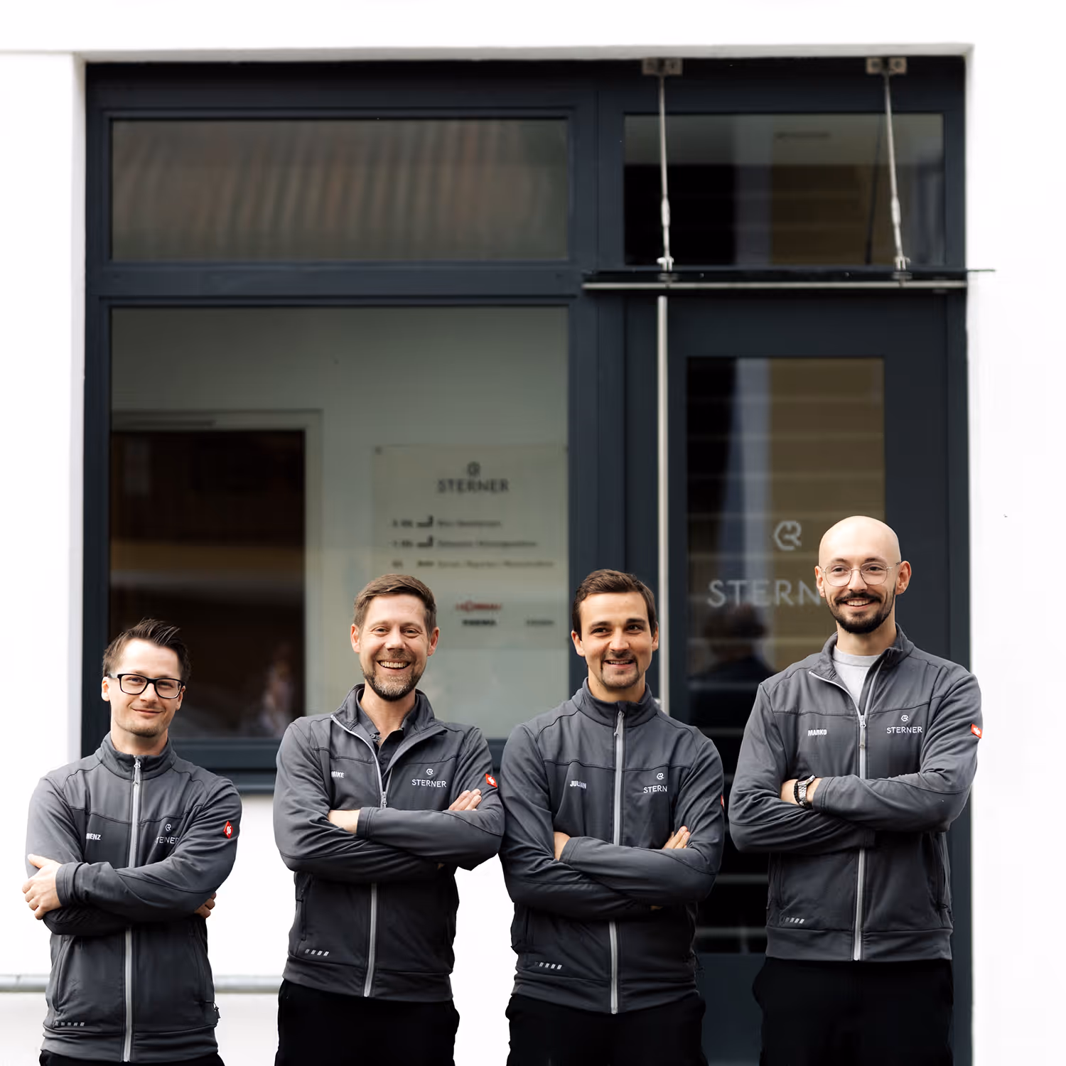 Gruppenfoto von 4 Männern in einer grauen Jacke